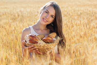 Young woman with fresh baked bread in grain crop