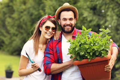 Couple outdoors holding up pot of mint